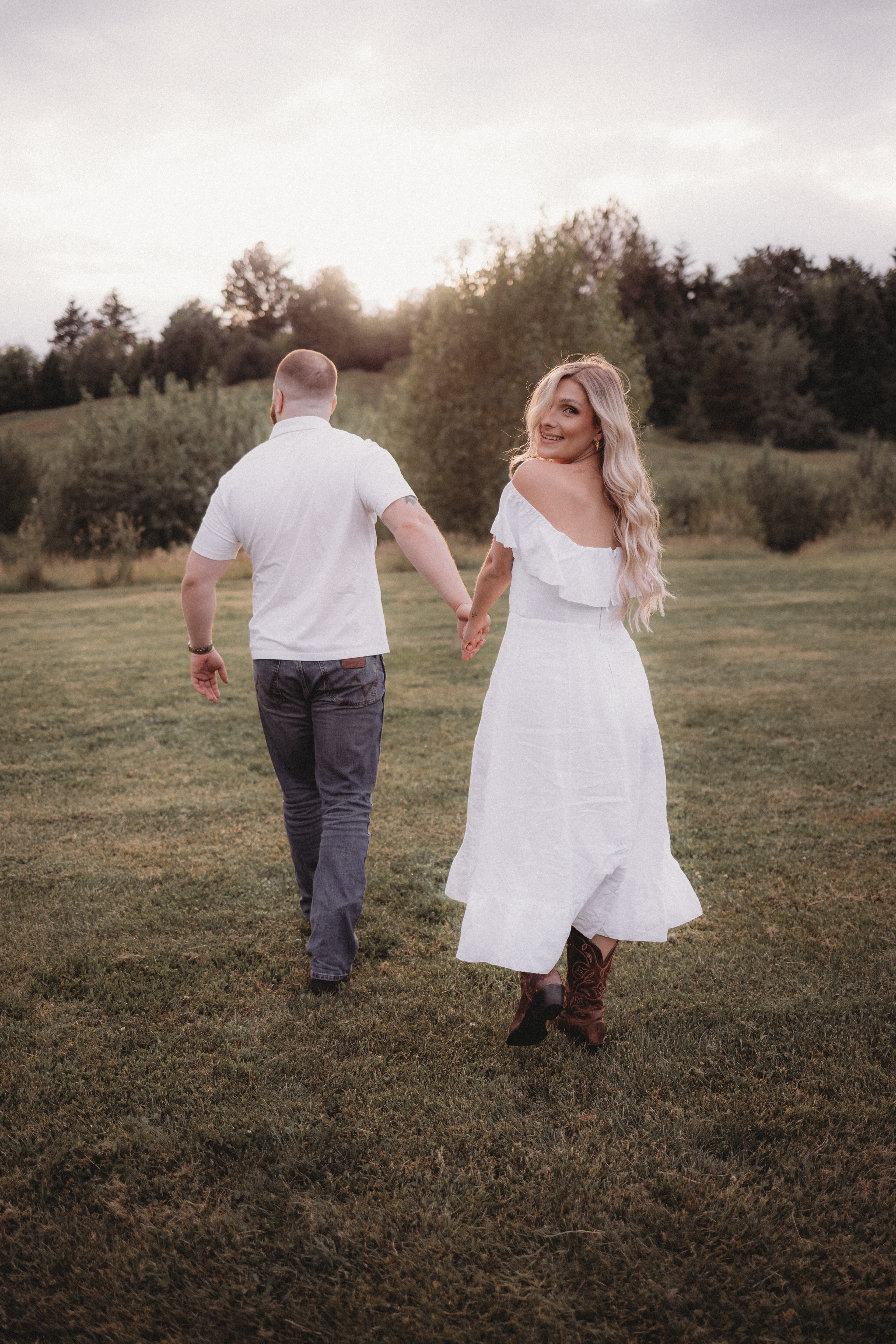 Matthew and Robyn walking through a field at golden hour