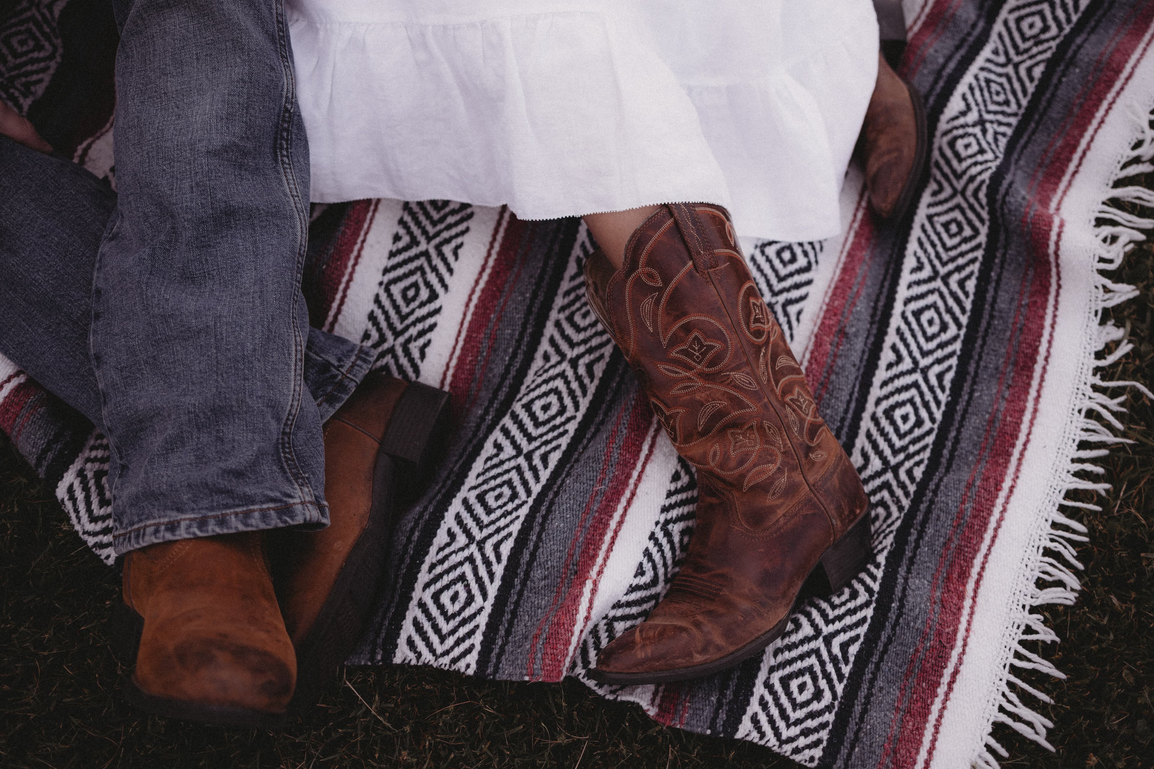 Cowboy boots and a woven blanket in the grass